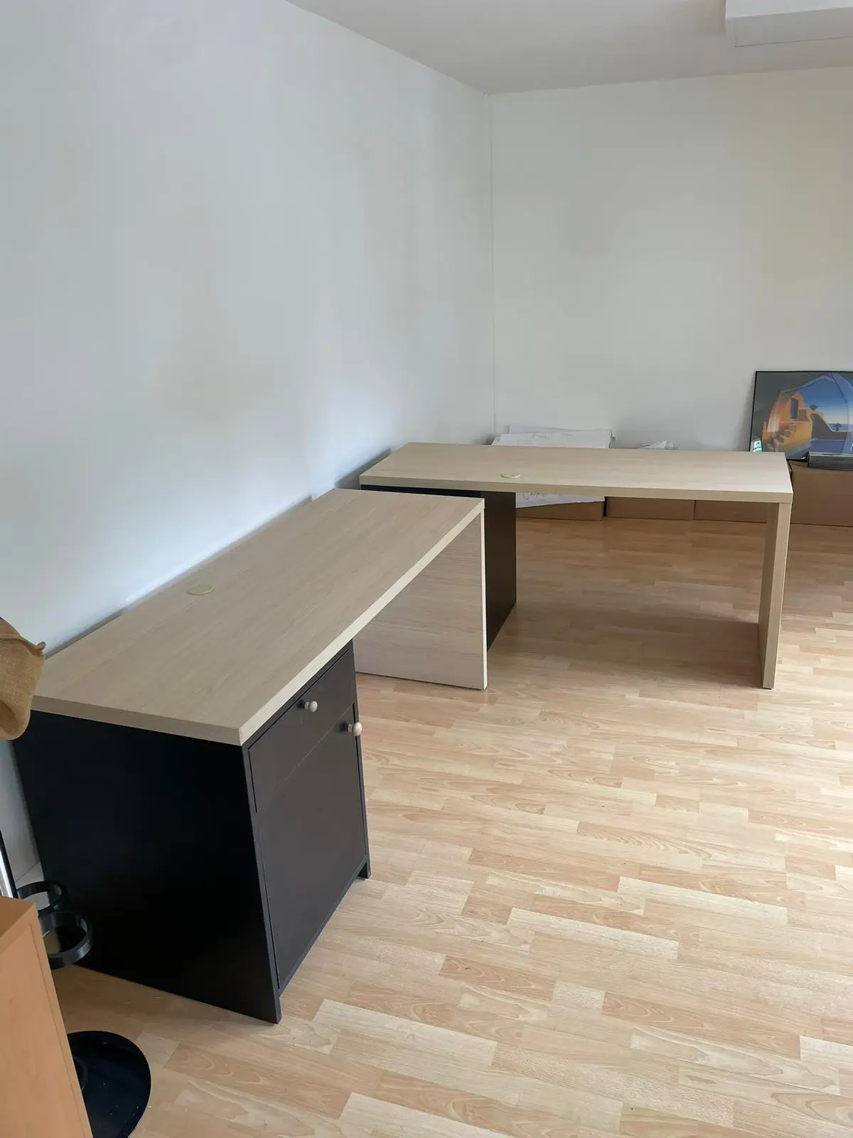 Deux postes de travail en décor chêne clair disposés en L avec caissons noirs à portes