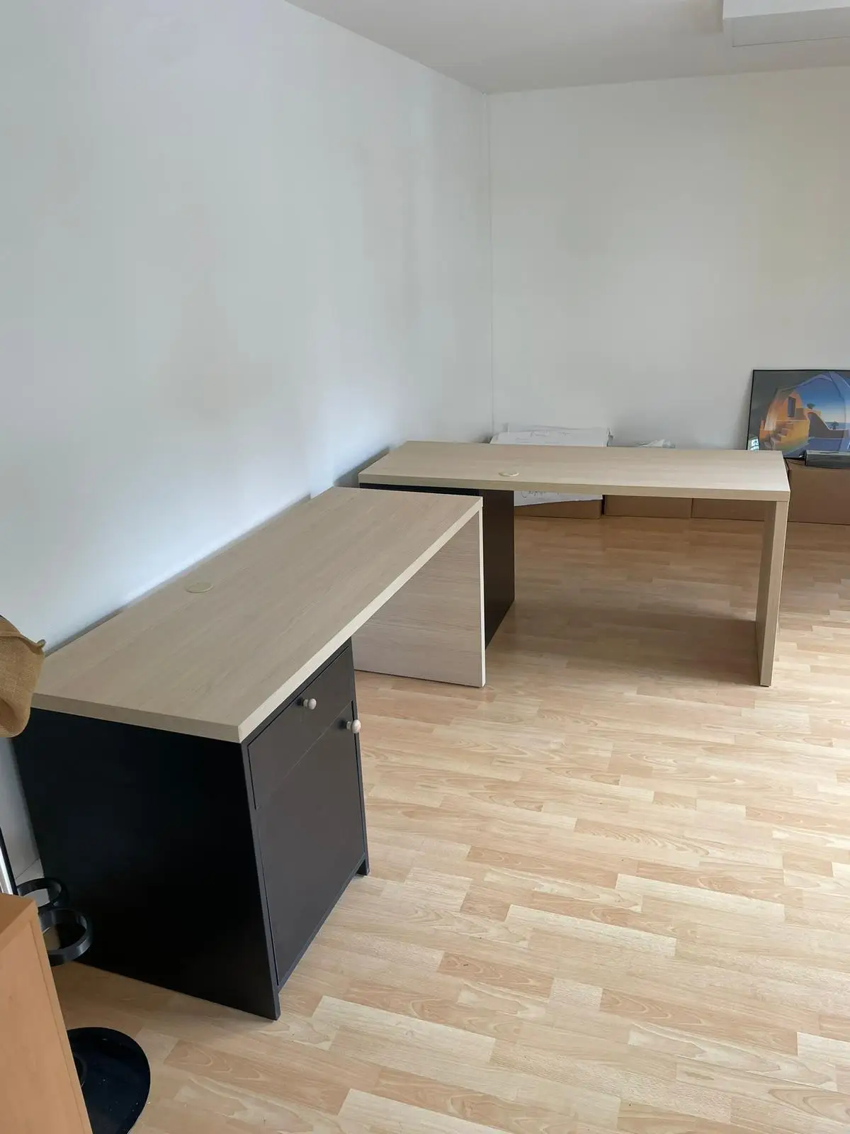 Deux postes de travail en décor chêne clair disposes en L avec caissons noirs a portes