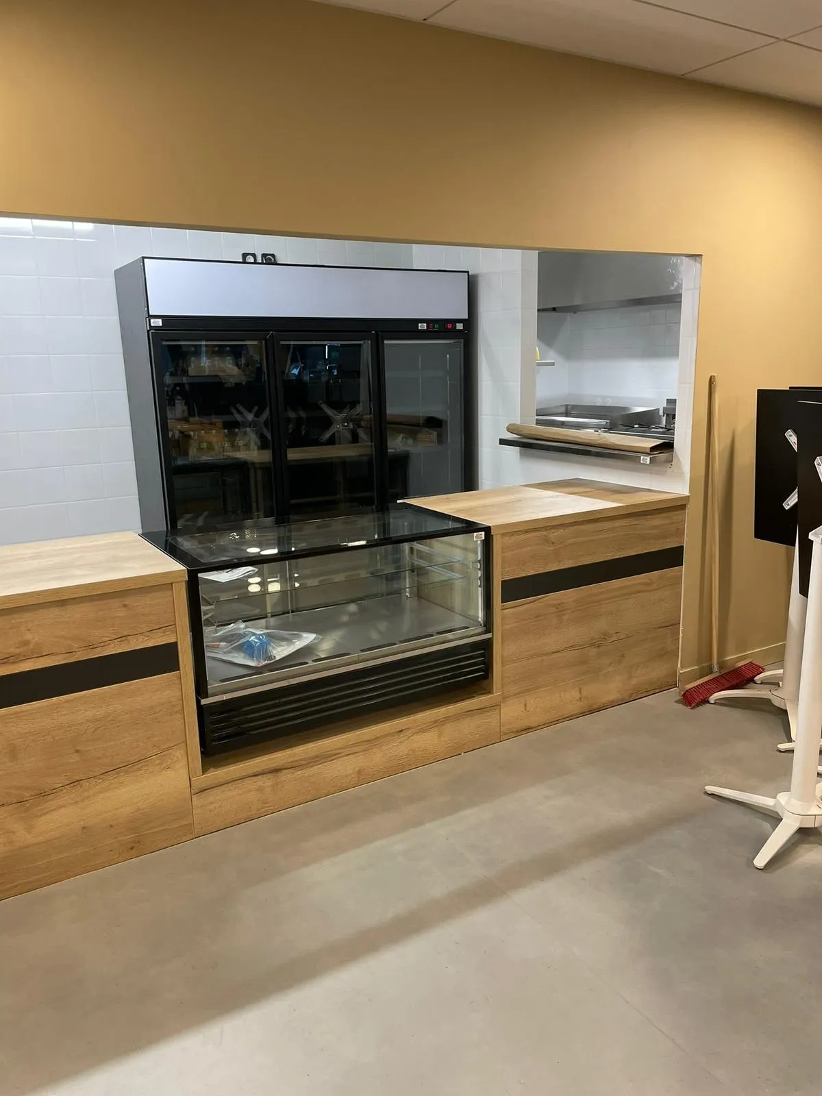 Comptoir de service décor chêne a bandeau noir avec vitrine réfrigérée et passe plat sur faïence blanche