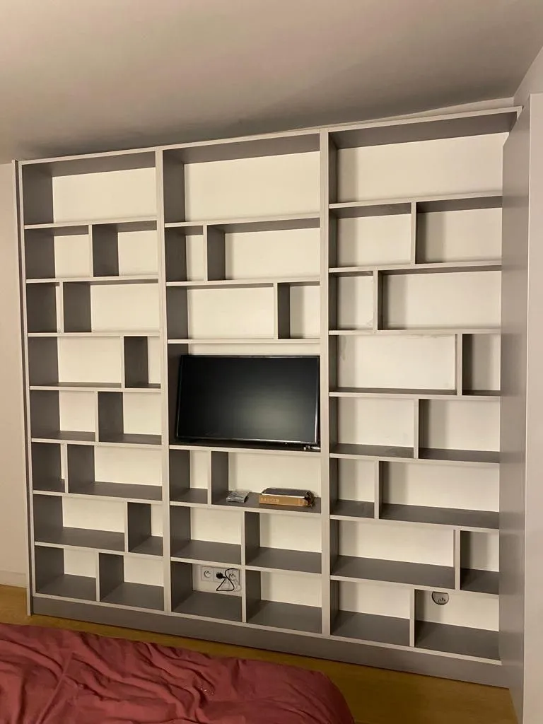 Bibliotheque murale toute hauteur a niches asymetriques blanches et grises avec emplacement televiseur central