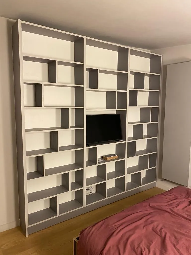 Bibliothèque sur mesure à niches irrégulières blanches et grises vue de trois quarts, radiateur à droite
