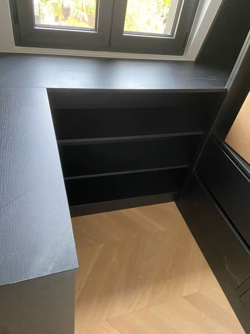 Bureau d’angle noir sur mesure sous fenêtre avec étagères basses et retour latéral