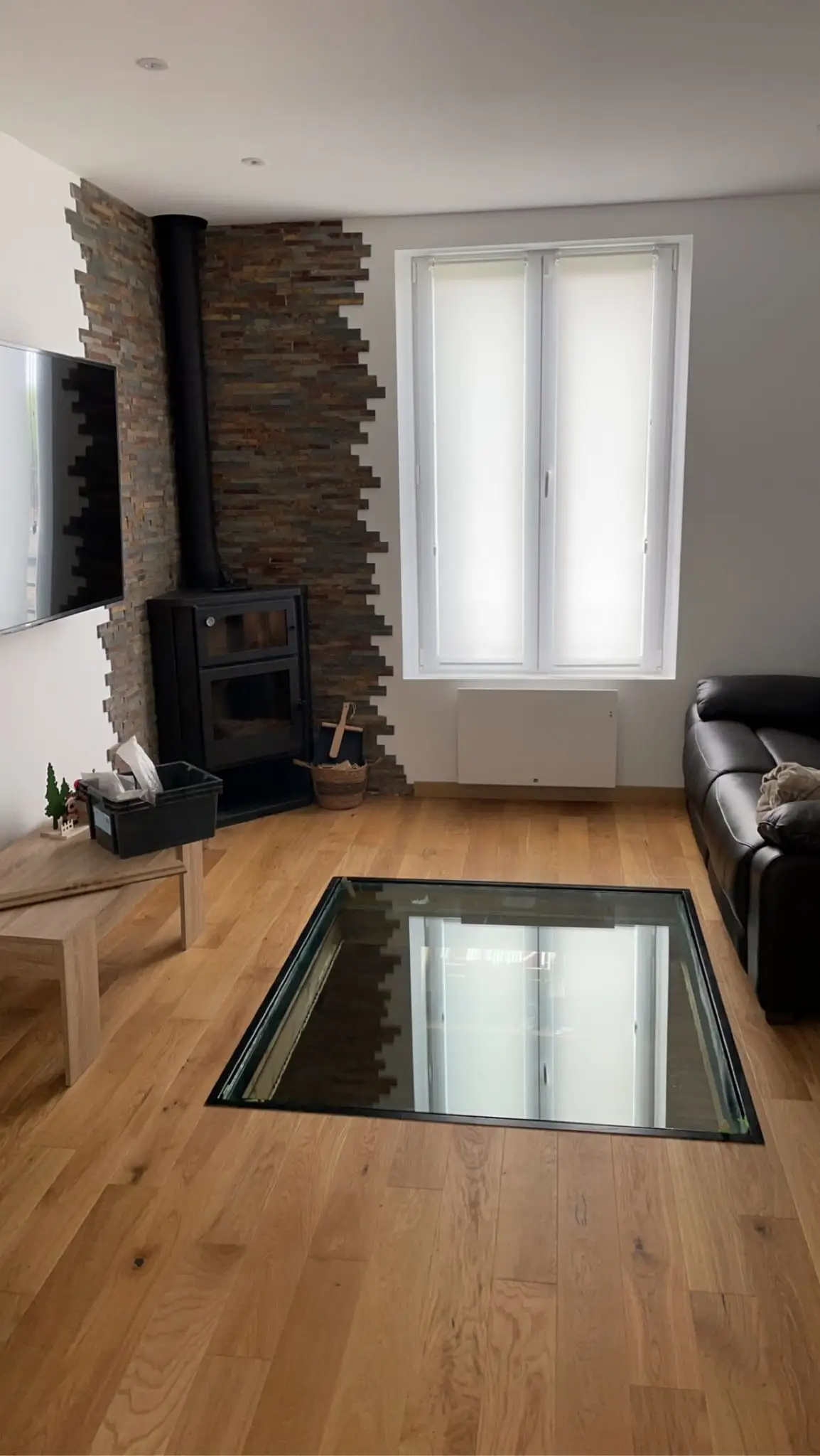 Sejour avec parquet chêne pose autour d'une tremie vitrée, poele a bois et parement pierre