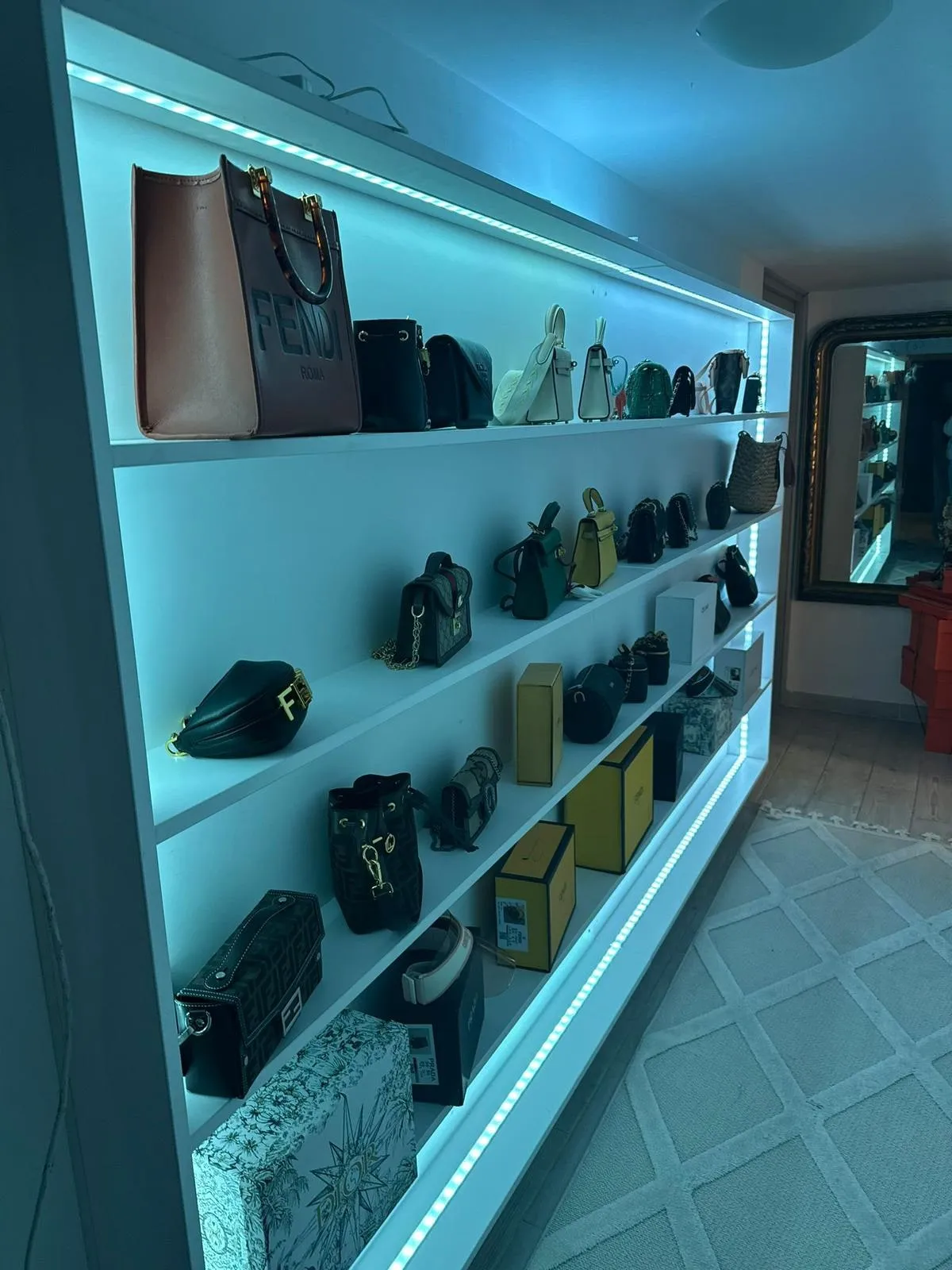Étagère murale blanche sur toute la longueur avec éclairage LED et sacs à main présentés