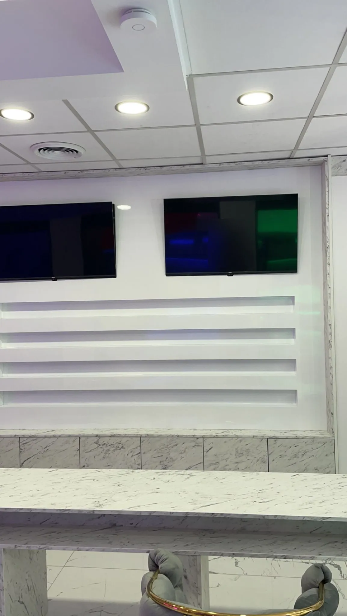 Mur de présentation avec quatre étagères laquées blanches retro-eclairees et deux ecrans